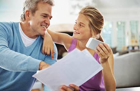 Father teaching his teen daughter about bills and money, teaching your teen how to save money